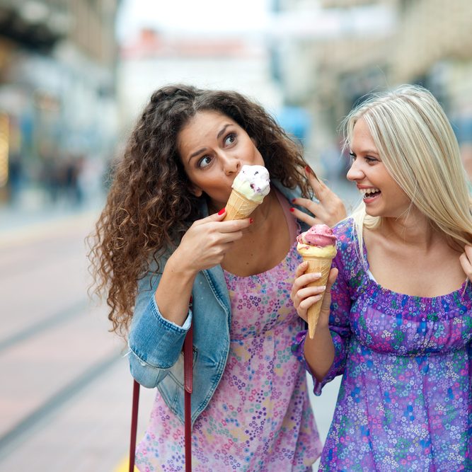 two women enjoying an ice cream cone after soft tissue laser dentistry